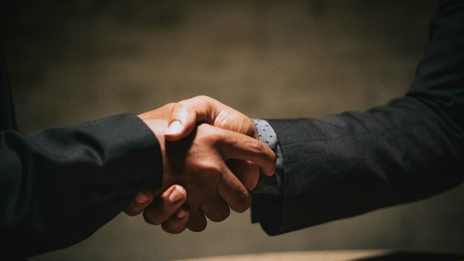 Close-up of two people in business suits shaking hands