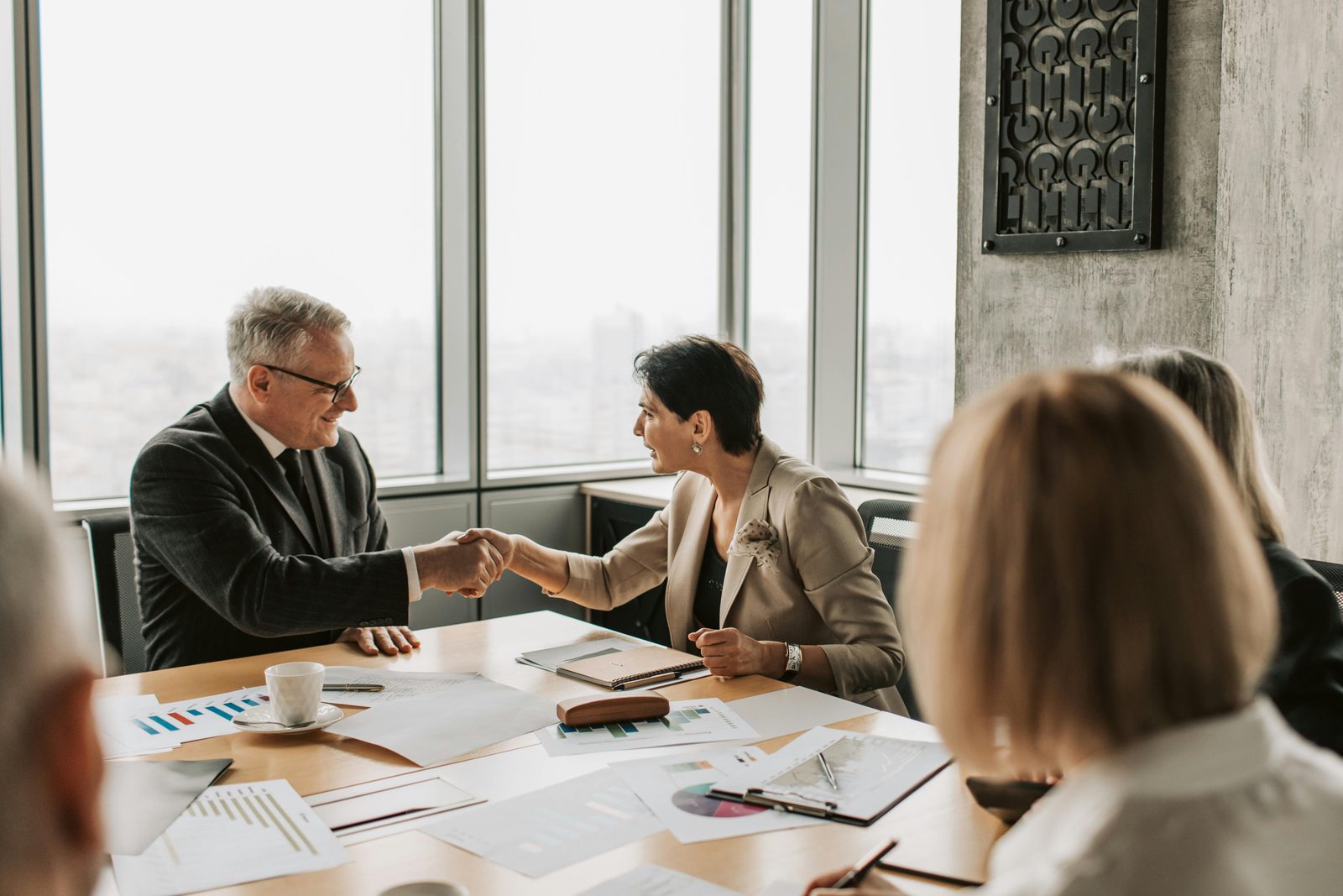 Advisers and clients seated around a boardroom table reviewing printed transaction documents